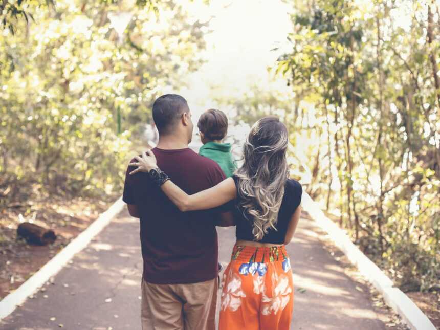 A couple with their young song walking on a road with their backs to the camera
