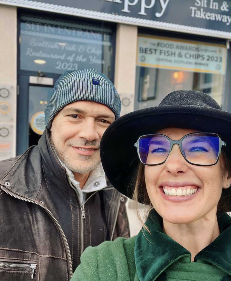 Husband and wife smiling in front of restaurant